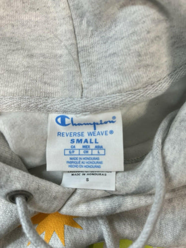Close-up of a light gray Champion hoodie showing the inner neck label with size information and drawstring cords.